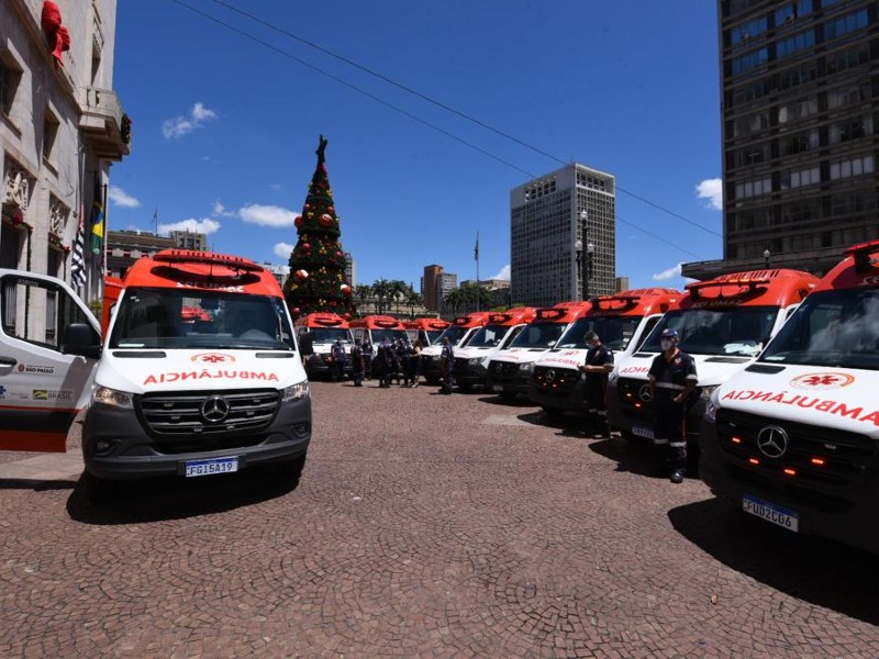 Ambulâncias do Samu enfileiradas no pátio de entrada da sede da Prefeitura. Elas são brancas com o teto pintado de vermelho e no capô da frente está escrito ambulância